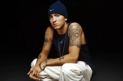 Eminem posing seriously in a black hoodie, with text overlay in Hindi and English highlighting his rise from Detroit struggles to global hip-hop fame, symbolizing his inspirational journey.