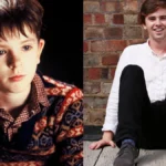 Freddie Highmore smiling in a black suit at an event, with text overlay in Hindi and English highlighting his inspiring journey from child actor to acclaimed star for AajKyaHai.com readers