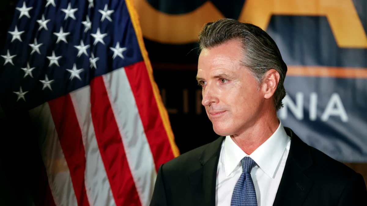 Gavin Newsom portrait with Hindi text 'गेविन न्यूसम की प्रेरणादायक जीवन यात्रा' on AajKyaHai.com