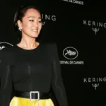 Gong Li smiling in a red dress, with Hindi text overlay 'गोंग ली की प्रेरणादायक कहानी' and English text 'Gong Li's Inspiring Journey'