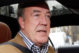 Jeremy Clarkson smiling in a car, celebrating his birthday with fans and co-hosts Richard Hammond and James May on The Grand Tour set, जेरेमी क्लार्कसन की जन्मदिन विशेष तस्वीर
