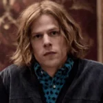 Jesse Eisenberg Hollywood actor smiling in a photoshoot, representing his inspiring journey from indie films to blockbuster hits like The Social Network, with Hindi text overlay for AajKyaHai.com audience