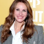 Julia Roberts smiling in a red carpet photo, with Hindi text overlay 'जूलिया रॉबर्ट्स की प्रेरणादायक जीवन कहानी' and English text 'Julia Roberts Inspirational Life Story'
