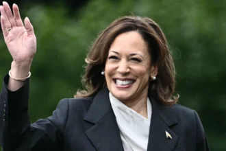 Kamala Harris smiling confidently in a professional setting, with Indian and American flags in background, representing her inspirational journey from California to Vice President
