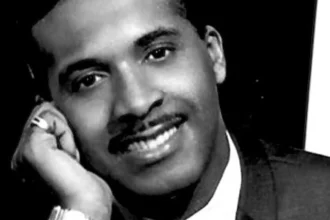 Levi Stubbs, the legendary lead singer of The Four Tops, performing on stage in a classic Motown era photo, with a vibrant background showcasing his powerful voice and soulful music.