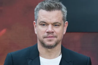 Matt Damon smiling in a black suit at a movie premiere, with text overlay in Hindi and English describing his life journey from struggle to Hollywood stardom