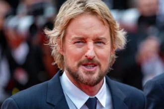 Owen Wilson smiling in a candid photo, with text overlay in Hindi and English highlighting his inspiring journey from struggles to Hollywood stardom