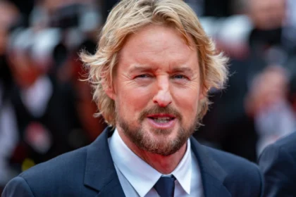 Owen Wilson smiling in a candid photo, with text overlay in Hindi and English highlighting his inspiring journey from struggles to Hollywood stardom