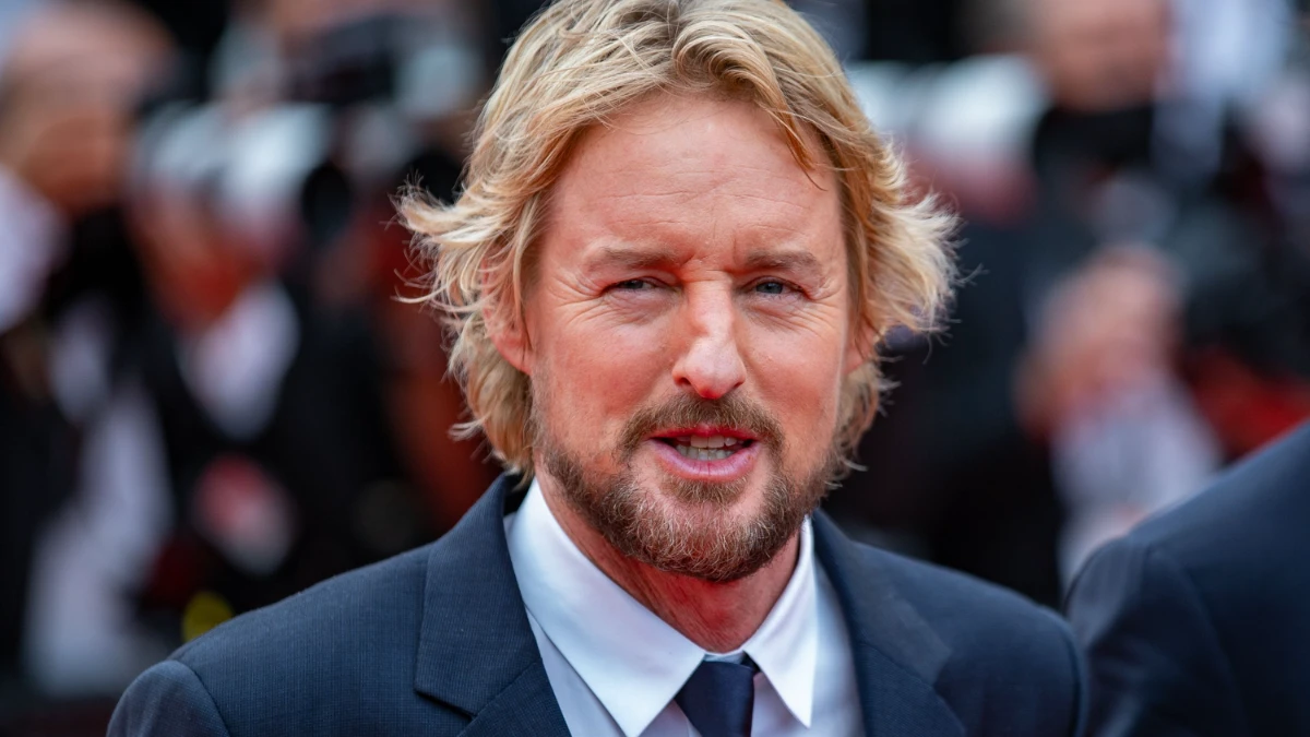 Owen Wilson smiling in a candid photo, with text overlay in Hindi and English highlighting his inspiring journey from struggles to Hollywood stardom