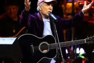 Paul Simon performing live on stage, showcasing his iconic guitar and soulful expression, representing his timeless musical legacy in Hindi and English