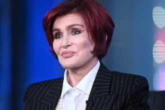 Sharon Osbourne smiling in a professional photoshoot, representing her inspiring life journey and career achievements in the entertainment industry.
