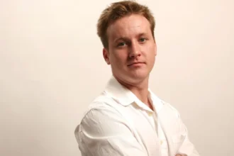 Tom Guiry smiling in a professional headshot, symbolizing his journey from struggle to success in Bollywood and Hollywood, with text overlay in Hindi and English