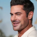 Zac Efron smiling in a professional photoshoot, from his High School Musical days to current Hollywood roles, showing his career evolution in Bollywood style